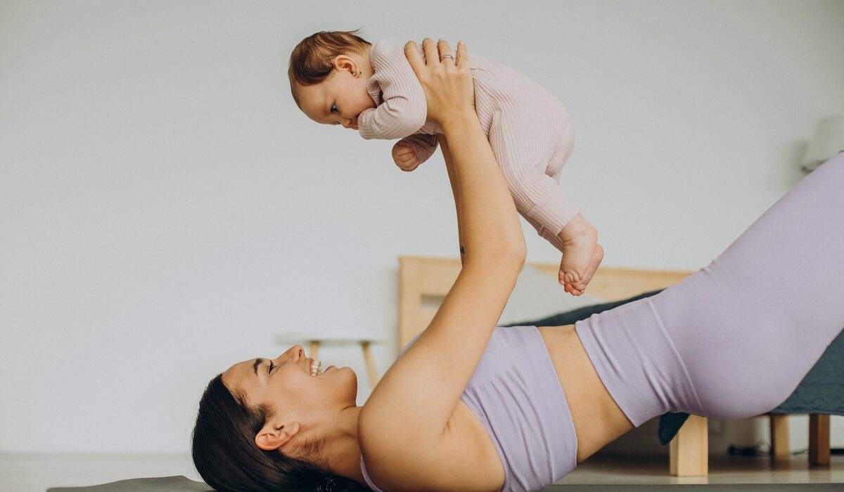 majka u predivnom ljubičastom setu drži bebicu u rukama na podlozi za vježbanje, BEBAiOna