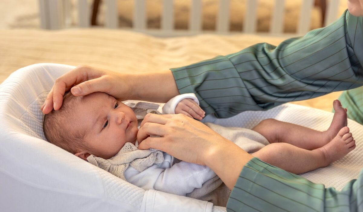 mama drži ruku na čelu tek rođene bebe